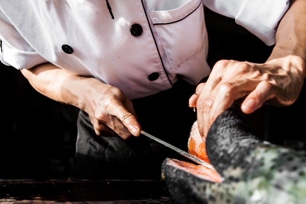 chef cuts into salmon